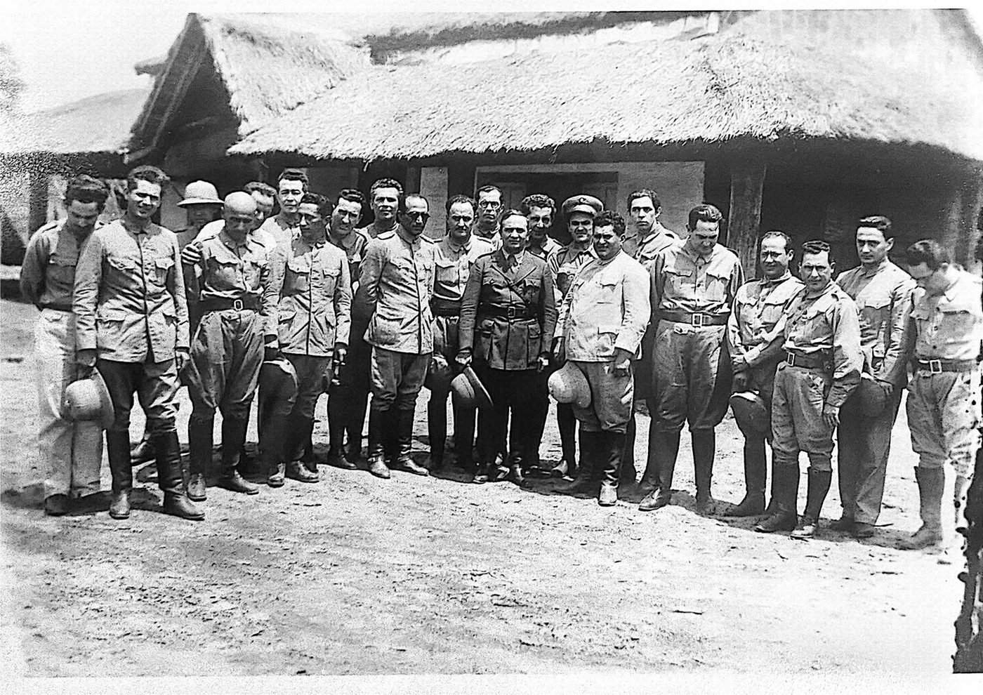 Grupo de oficiales y civiles ante una construcción de campaña. Sin epígrafe original; de la serie de la movilización de la Guerra del Chaco. No se identifica a