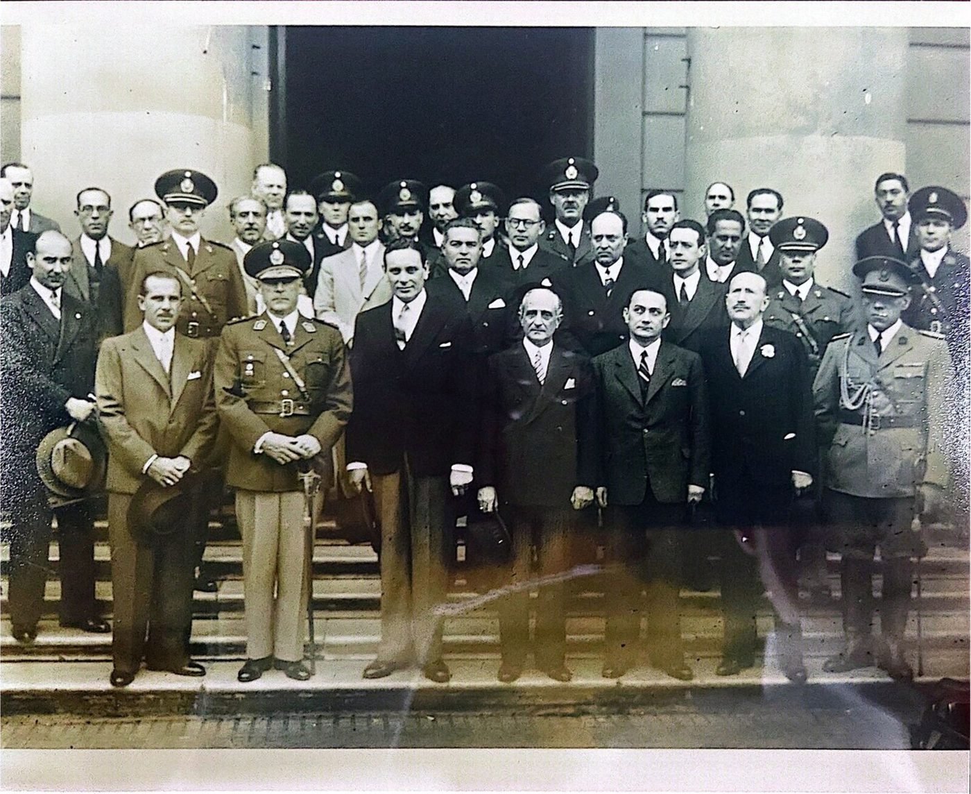 Fotografía oficial en la escalinata de un edificio neoclásico: unos treinta y cinco hombres, entre ellos oficiales superiores del ejército y de la policía. Sin